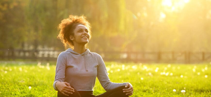 Happy,Young,Woman,Sitting,Outdoors,In,Yoga,Position